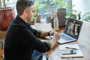 A man on a video chat with a woman working on his laptop from home 