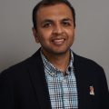 Srikrishnan Ganesan headshot in a checked shirt and suit