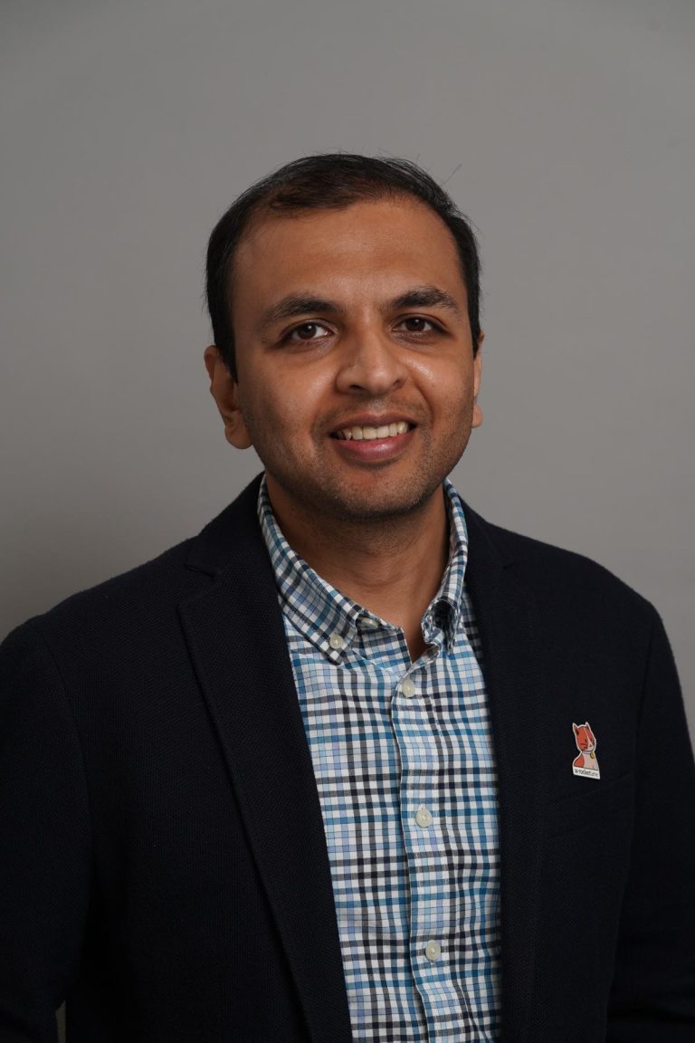 Srikrishnan Ganesan headshot in a checked shirt and suit
